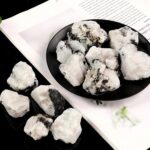 Close-up of white mineral rocks with black inclusions on a black and white background, showcasing natural mineral textures and formations.