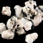 White and black mineral rocks on black background, close-up view.