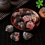 Assorted rough natural minerals on a wooden plate, showcasing various colors and textures, ideal for educational and decorative purposes.