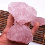 Large pink Himalayan salt crystals held in hand, showcasing their natural texture and color, ideal for science experiments, decor, and educational purposes.