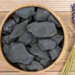 Collection of black slate rocks in a round wooden bowl, ideal for science experiments, educational activities, or decorative purposes.