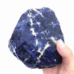 Hand holding a large, dark blue mineral rock with white veins, ideal for science decor and educational toys.