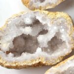 Close-up of a sparkling geode with crystalline interior and rough outer surface, showcasing natural mineral formations.