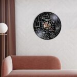 Physics-themed wall clock featuring scientific symbols and illustrations on a black background.