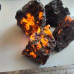 Close-up of volcanic rocks with glowing orange lava-like cracks, showcasing natural volcanic textures and fiery appearance.