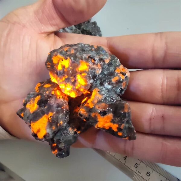 Meteorite with glowing interior under hand, scientific specimen for educational display.