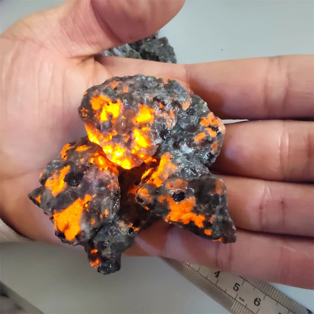 Meteorite with glowing interior under hand, scientific specimen for educational display.