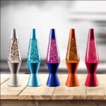 Colorful lava lamps with glittery liquid in various shades including silver, blue, pink, orange, and red, displayed on a wooden surface.