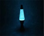A glowing lava lamp with a black base and a transparent tube filled with glitter and colored liquid, emitting a calming blue light in a dark room.