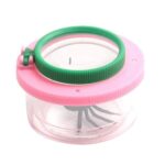 Miniature magnifying glass with a pink and green frame, containing a small insect inside the transparent container.