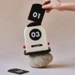 A playful October flip calendar with black and white cards displaying the date, balanced on a smooth stone, perfect for educational and decorative purposes.