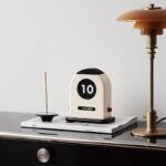 Stylish retro flip clock displaying the date "October 10" on a sleek desk, paired with a modern table lamp, perfect for contemporary home or office decor.
