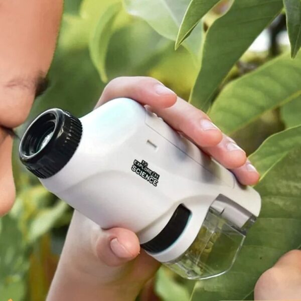 A child examining leaves with a handheld microscope in a garden.