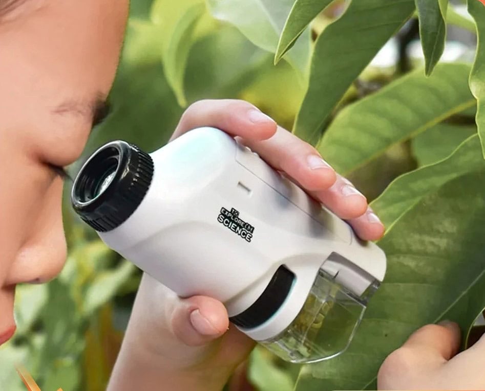 A child examining leaves with a handheld microscope in a garden.