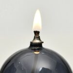 Burning candle with a black wax exterior and a visible wick, producing a small flame. Perfect for science-themed decor or educational demonstrations.