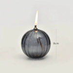 Glass spherical vase with a lit candle and flame, measuring approximately 8cm in height, showcasing a modern and elegant design.