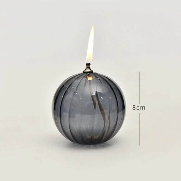 Glass spherical vase with a lit candle and flame, measuring approximately 8cm in height, showcasing a modern and elegant design.
