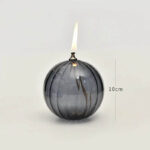 A glass spherical candle with a lit flame, approximately 10cm tall, showcasing a contemporary and elegant design perfect for home decor or educational demonstrations.