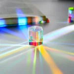 Transparent crystal prism creating colorful rainbow light patterns on a white surface, showcasing light refraction and dispersion effects.