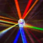 A clear crystal prism creating vibrant rainbow light beams on a dark surface, demonstrating light refraction and dispersion for educational science experiments.