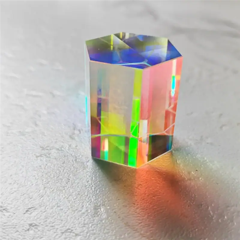 Hexagonal Prism Optical Crystal Colorful holographic hexagonal prism optical crystal with rainbow reflections on a textured surface.