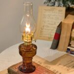 Vintage oil lamp with glass chimney and brass base, placed on an old book, creating a nostalgic and historical ambiance.
