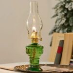 Antique-style green glass oil lamp featuring a clear glass chimney and brass accents, perfect for vintage decor or educational demonstrations about traditional lighting methods.