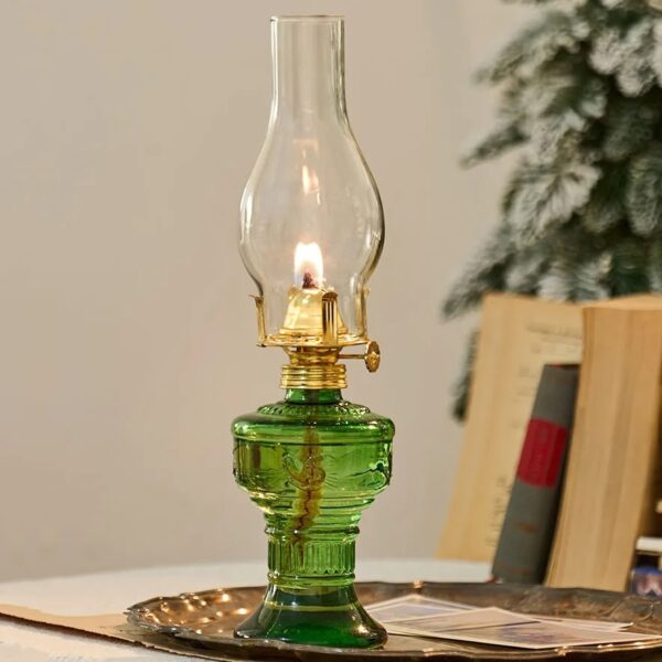Antique-style green glass oil lamp featuring a clear glass chimney and brass accents, perfect for vintage decor or educational demonstrations about traditional lighting methods.