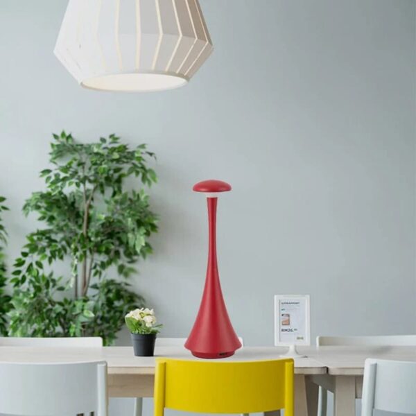 Stylish red science-inspired lamp placed on a white table in a modern room with a potted plant and minimal decor.