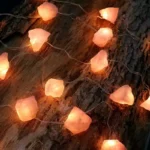 String of warm-colored glow stones lights on a rustic wooden surface, creating a cozy and inviting atmosphere.