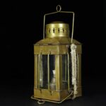 Antique brass lantern with glass panels and a handle, vintage decorative piece.