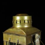 Vintage brass oil lantern with a wick and handle, ideal for decorative or educational purposes in science and history displays.
