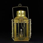 Vintage metal lantern with glass panels, chain handle, and decorative details.