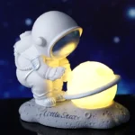 Adorable astronaut figurine with a glowing moon globe, perfect as a space-themed night light or educational decor for kids' rooms.