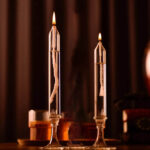 Two glass test tubes with lit candles inside, showcasing a science experiment setup for educational demonstrations.