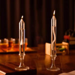 Elegant glass candle holders with lit candles on a wooden table, creating a warm and inviting atmosphere. Perfect for science-themed decor and educational displays.