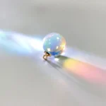 Rainbow light reflection on a glass marble casting colorful shadows.