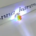 Brightly colored glass orb with LED lights casting colorful reflections on a white surface.
