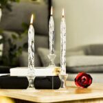 Elegant glass candle holder with three lit candles on a wooden surface.