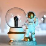 Innovative science gadget featuring a miniature astronaut figure next to a glass dome with a black light bulb inside. Perfect for science enthusiasts and educational decor.
