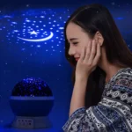 Woman enjoying a starry sky projection with moon and stars on a dark background.