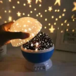 Hand holding a star projector night light casting star-shaped shadows on the wall, creating a cozy celestial ambiance in a dark room.
