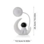 Cute space-themed night light featuring an astronaut sitting on a crescent moon with a connected lamp, ideal for children's bedrooms and educational decor.