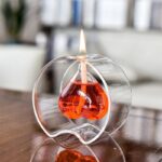 Glass oil lamp with a flame and orange liquid inside, decorative science-inspired piece.