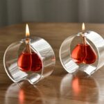 Red liquid-filled glass candle holder with a lit candle inside, showcasing a modern and stylish design.