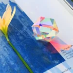 Colorful optical crystal prism with rainbow reflections on a blue surface.