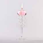 Elegant pink candle burning in a clear glass holder with a spiral stem, perfect for science decor and educational displays.
