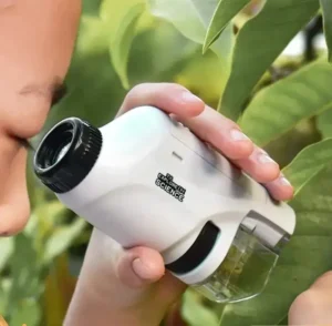 Child examining plant leaves with a handheld microscope featuring LED illumination, ideal for educational science exploration.