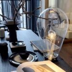 Elegant glass light bulb art piece with branches, creating a contemporary decor element.