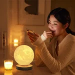 Young woman enjoying the warm glow of a moon-shaped lamp in a cozy room, creating a relaxing atmosphere.